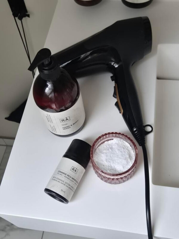 Ceramide fuktighetskrem fra RÅ Skincare for sensitiv hud på badet sammen med hårføner og toalettartikler.