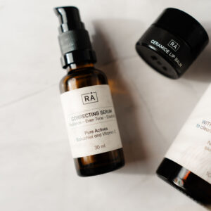 raw correcting serum lies on a light background together with ceramide lip balm and cleanser