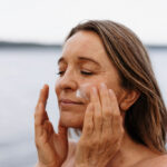 Voksen kvinne som påfører rå skincare ansiktskrem ute