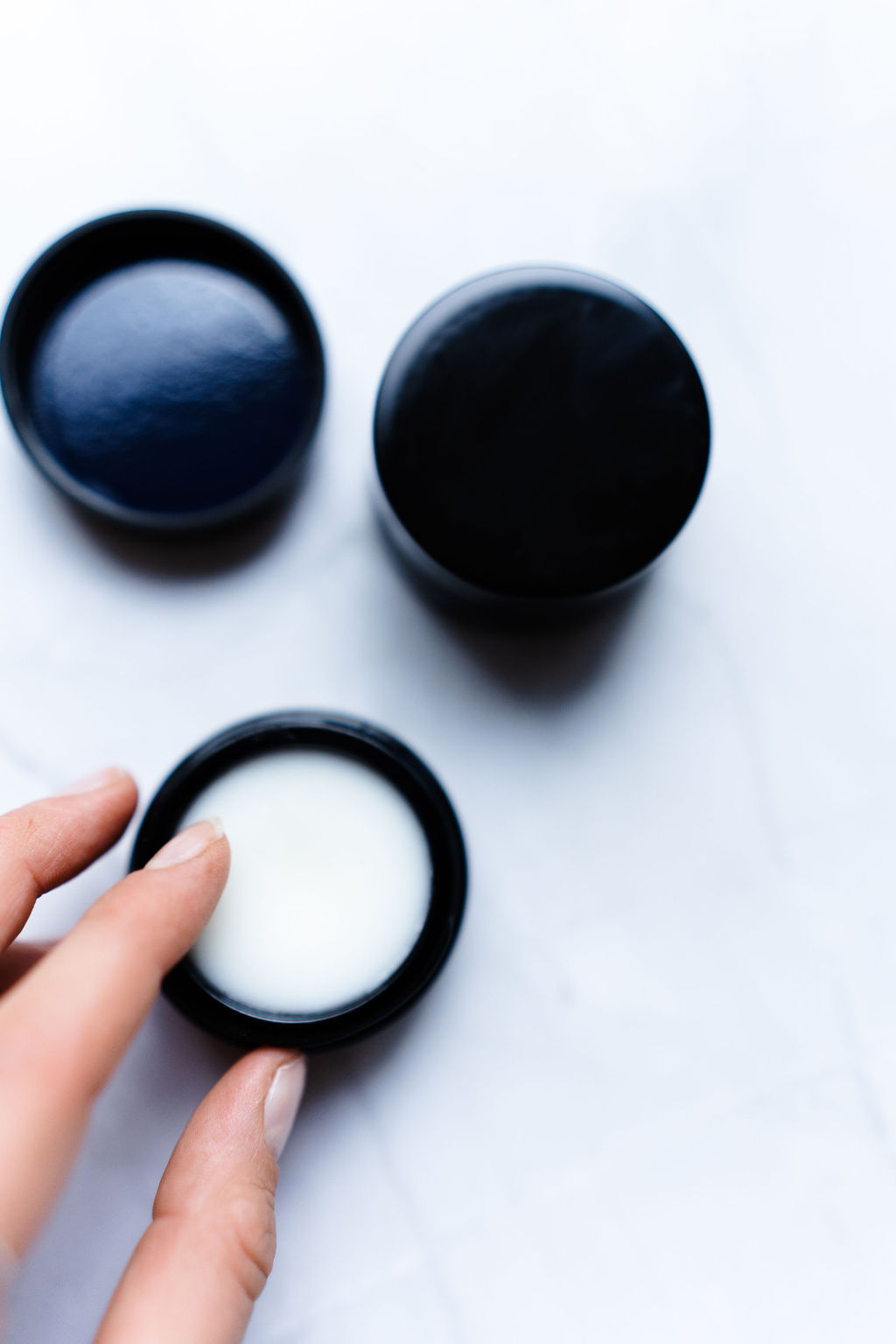 Sos ceramide balm. Krukken er åpen og en dame tar fingen oppi for å ta ut krem