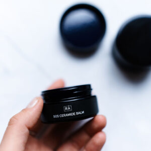 Sos ceramide balm is held in the hand so you can see the label on the product